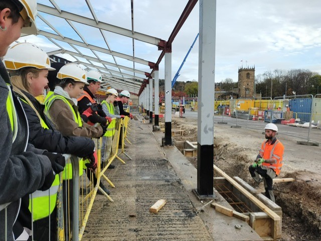 students outdoors with PPE listening to construction worker talk