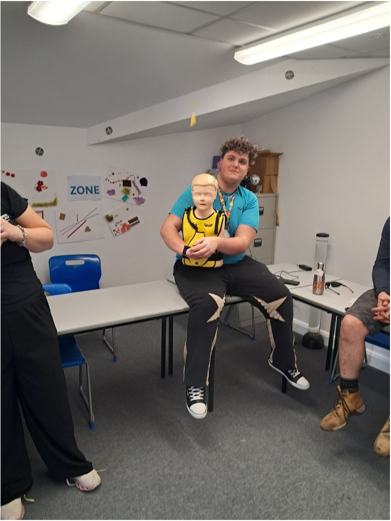 student sat down holding CPR adult mannequin